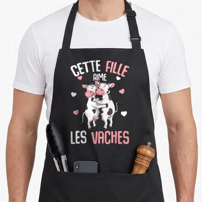 Tablier de cuisine noir avec deux vaches s'embrassant et le texte Cette Fille Aime Les Vaches Enfants.