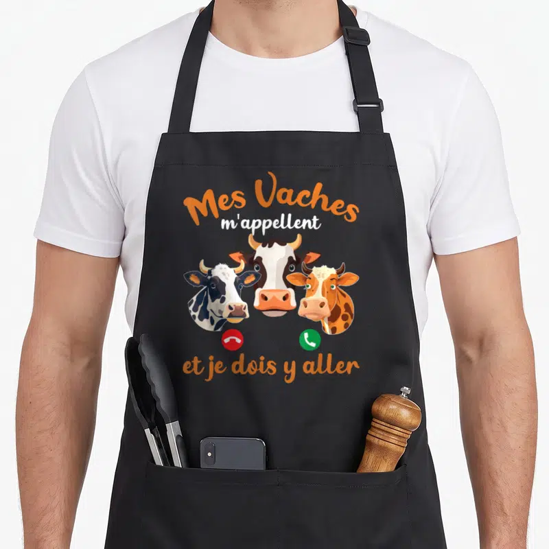 Tablier de cuisine noir avec trois têtes de vaches et le texte Mes Vaches m'appellent et je dois y aller.