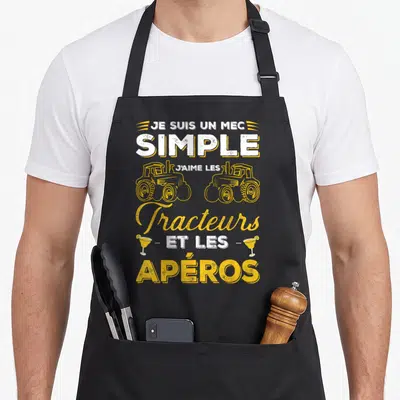 Tablier de cuisine noir avec l'inscription Je suis un mec simple j'aime les tracteurs et les apéros en typographie jaune et blanche.