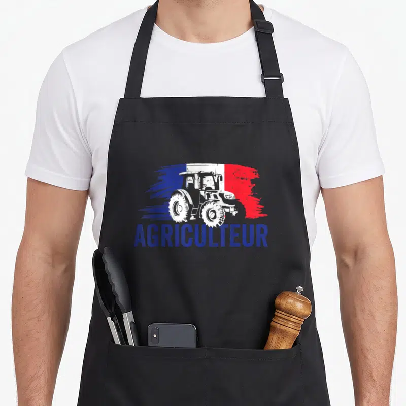 Tablier de cuisine noir avec illustration de tracteur blanc sur fond tricolore et le mot Agriculteur en bleu.