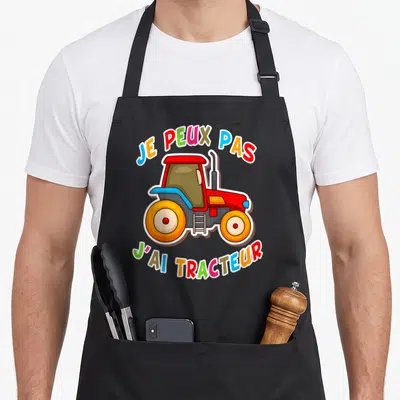 Tablier de cuisine noir avec illustration de tracteur rouge et texte multicolore Je peux pas j'ai tracteur.