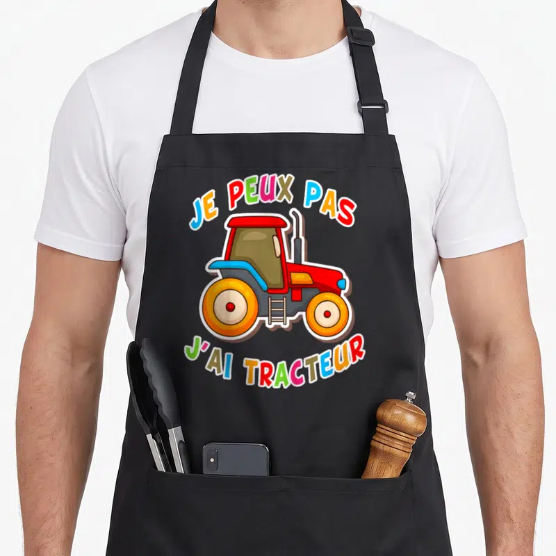 Tablier de cuisine noir avec illustration de tracteur rouge et texte multicolore Je peux pas j'ai tracteur.