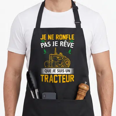 Tablier de cuisine noir avec texte je ne ronfle pas je rêve que je suis un tracteur et illustration de tracteur jaune.