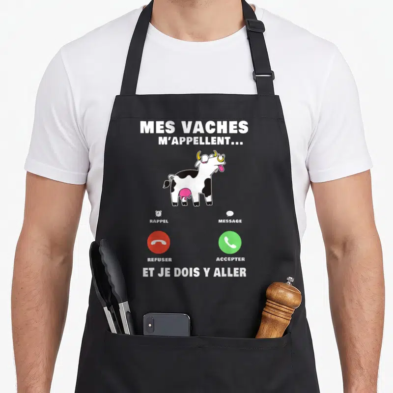 Tablier de cuisine noir avec une vache dessinée et des boutons d'appel téléphonique imprimés en blanc, rouge et vert.