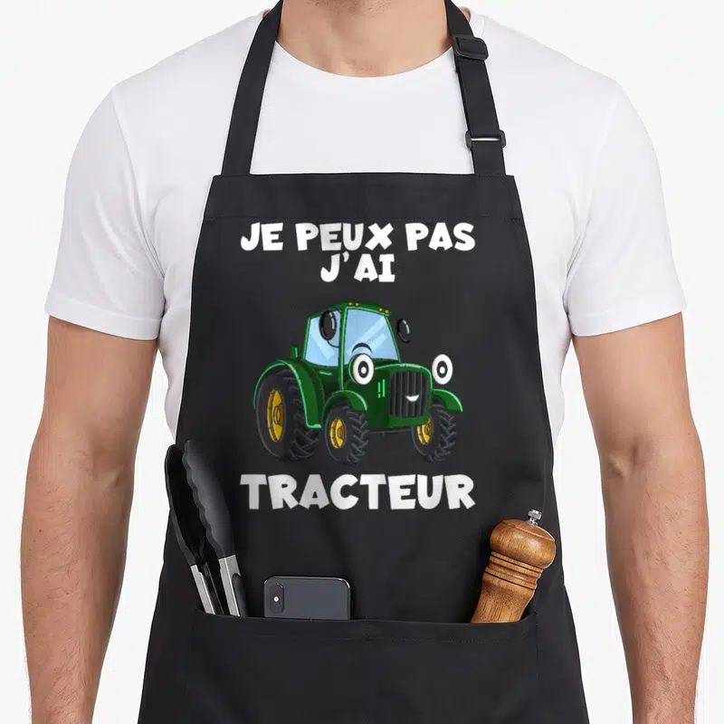 Tablier de cuisine noir avec illustration d'un tracteur vert souriant et texte blanc Je peux pas j'ai tracteur