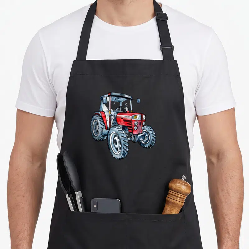 Tablier de cuisine noir avec illustration d'un tracteur Masey Ferguson 399 rouge et gris aux roues crantées.