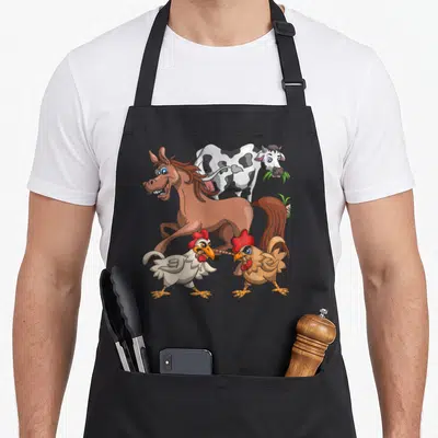 Tablier de cuisine noir avec illustration colorée d'un cheval, d'une vache et de deux poulets en train de se disputer une brindille.