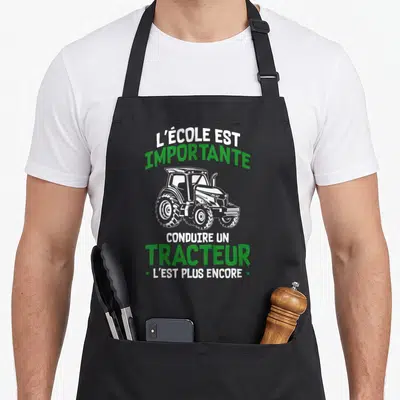 Tablier de cuisine noir avec illustration de tracteur et texte humoristique sur l'école et la conduite.