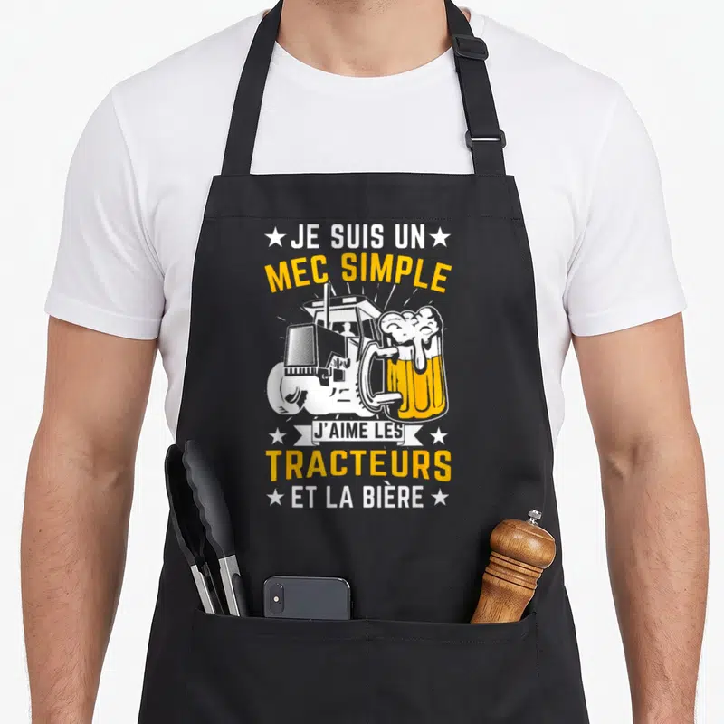 Tablier de cuisine noir avec illustration de tracteur et verre de bière jaune et blanc.