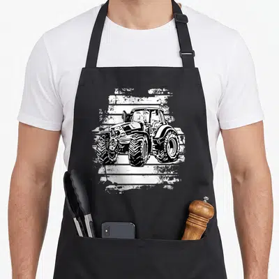 Tablier de cuisine noir avec illustration blanche d'un tracteur Deutz sur fond texturé rustique.