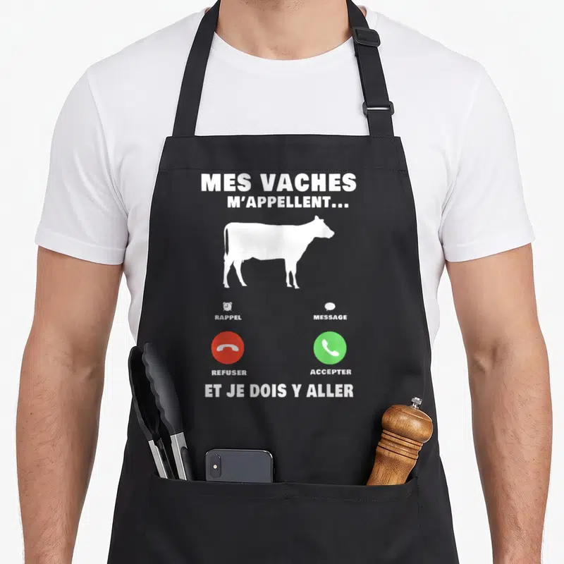 Tablier de cuisine noir avec silhouette blanche de vache et boutons d'appel téléphonique rouge et vert imprimés au centre.