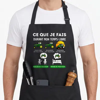 Tablier de cuisine noir avec illustration humoristique sur le temps libre d'un homme passionné par la conduite et le dessin de tracteurs verts.