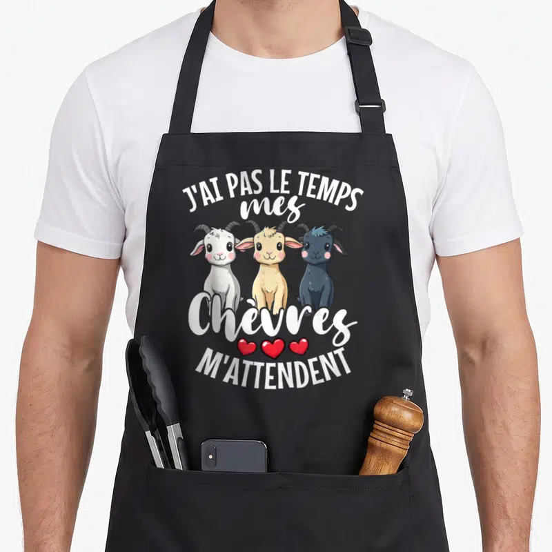 Tablier de cuisine noir avec trois chevreaux blancs, beige et noirs sous une inscription blanche humoristique.