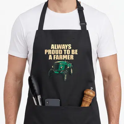 Tablier de cuisine noir avec inscription Always proud to be a farmer et illustration de tracteur vert vintage.