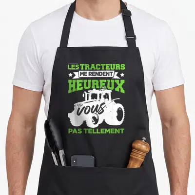 Tablier de cuisine noir avec illustration blanche de tracteur et texte vert lime humoristique.