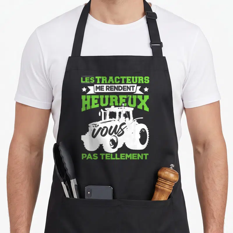 Tablier de cuisine noir avec illustration blanche de tracteur et texte vert lime humoristique.