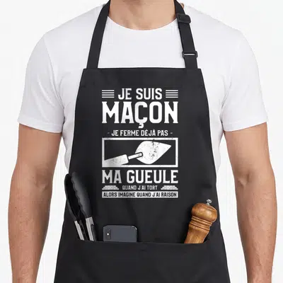 Tablier de cuisine noir avec inscription blanche Je Suis Maçon et illustration de truelle dans un style graphique vintage.
