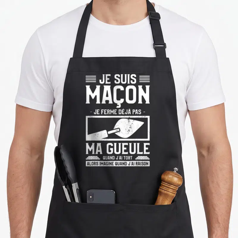 Tablier de cuisine noir avec inscription blanche Je Suis Maçon et illustration de truelle dans un style graphique vintage.