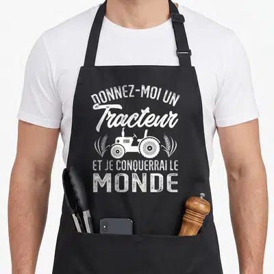 Tablier de cuisine noir avec inscription blanche Donnez-moi un tracteur et je conquerrai le monde accompagnée d'une illustration de machine agricole.