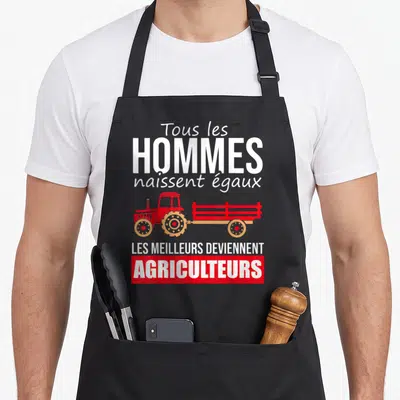 Tablier de cuisine noir avec inscription Tous les hommes naissent égaux et illustration de tracteur rouge tirant une remorque.