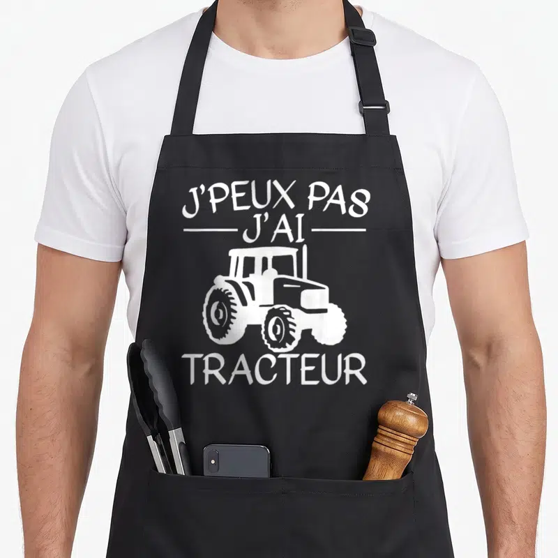 Tablier de cuisine noir avec inscription Je peux pas j'ai tracteur et silhouette blanche de machine agricole.