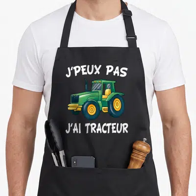 Tablier de cuisine noir avec illustration d'un tracteur vert et texte blanc J'peux pas j'ai tracteur