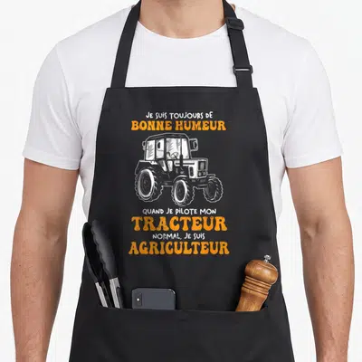 Tablier de cuisine noir avec illustration de tracteur et texte Je suis toujours de bonne humeur tracteur agriculteur en orange et blanc.