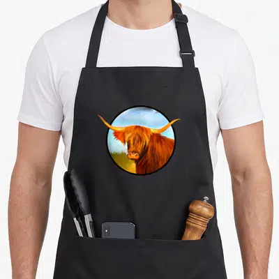 Tablier de cuisine noir avec illustration circulaire d'une vache Highland écossaise rousse aux longues cornes courbées.