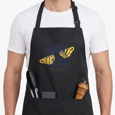 Tablier de cuisine noir avec logo Central Perk Friends en bleu et jaune sur fond gris uni.