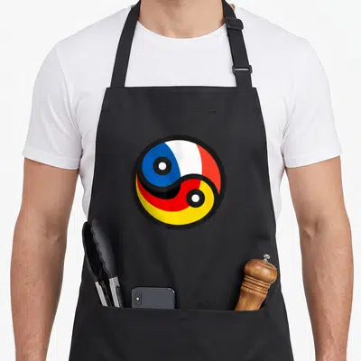 Tablier de cuisine noir avec un motif circulaire combinant les couleurs des drapeaux français et allemand en style yin yang.