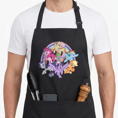 Tablier de cuisine noir avec illustration colorée de six poneys et un dragon sous un arc-en-ciel pastel.