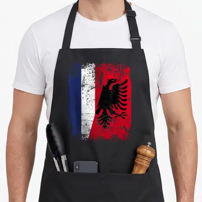 Tablier de cuisine noir avec un drapeau fusionnant le tricolore français et l'aigle noir albanais en texture usée.