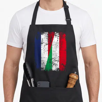 Tablier de cuisine noir avec un drapeau stylisé combinant les bandes tricolores française et italienne dans un effet vieilli.