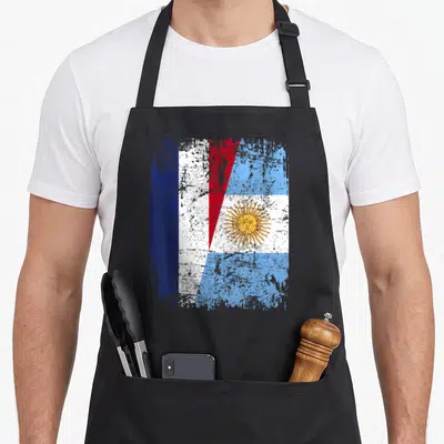 Tablier de cuisine noir avec un drapeau fusionnant les couleurs de l'Argentine et de la France dans un style vieilli.