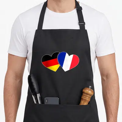 Tablier de cuisine noir avec deux cœurs superposés aux couleurs des drapeaux français et allemand.