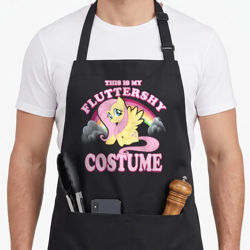 Tablier de cuisine noir avec l'illustration de Fluttershy et le texte This Is My Fluttershy Costume en lettres roses.