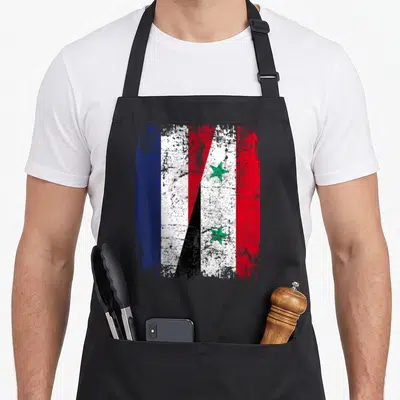 Tablier de cuisine noir avec un motif de drapeau combinant les couleurs de la Syrie et de la France en style usé.