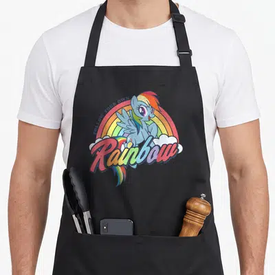 Tablier de cuisine noir avec illustration d'un poney bleu aux cheveux multicolores devant un arc-en-ciel et des nuages blancs.