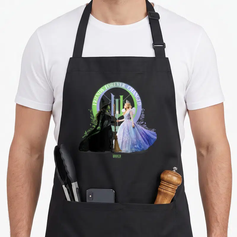 Tablier de cuisine noir avec Glinda et Elphaba tenant une baguette sous l'arc Friends Forever Changed