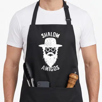Tablier de cuisine noir avec illustration blanche d'un Rabin au chapeau et lunettes rondes portant les mots Shalom Amigos.