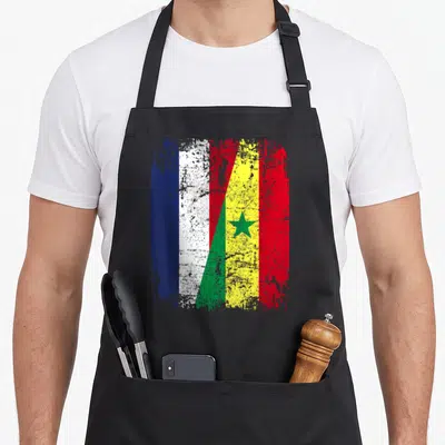 Tablier de cuisine noir avec un drapeau combinant les couleurs du Sénégal et de la France en style vieilli.