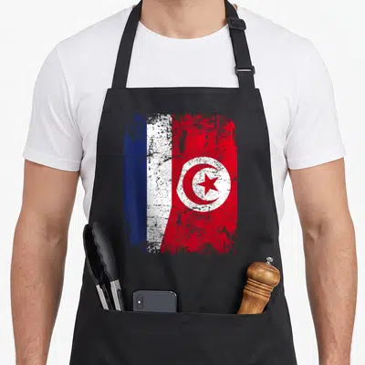 Tablier de cuisine noir avec un motif représentant le drapeau de l'amitié fusionnant les drapeaux français et tunisien en style délavé.