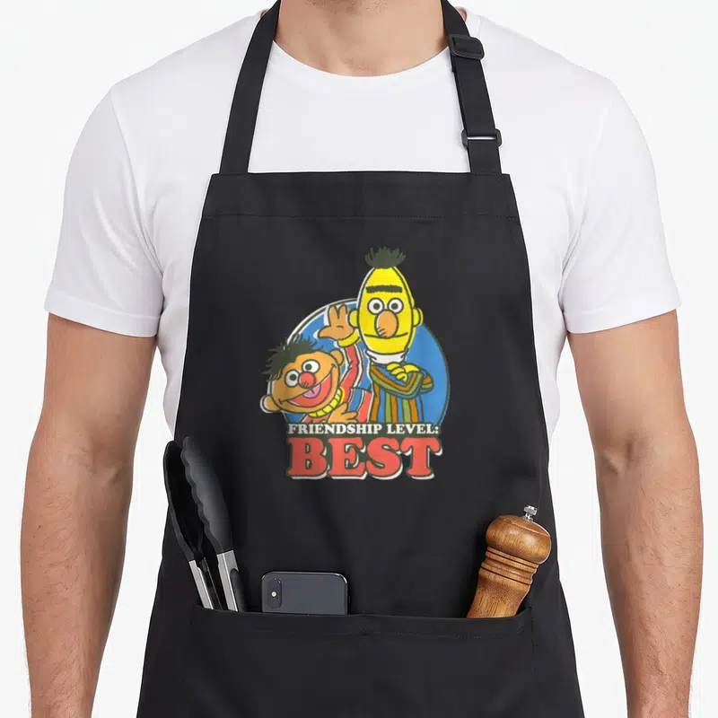 Tablier de cuisine noir avec Bert et Ernie et l'inscription Friendship Level Best en lettres rouges.