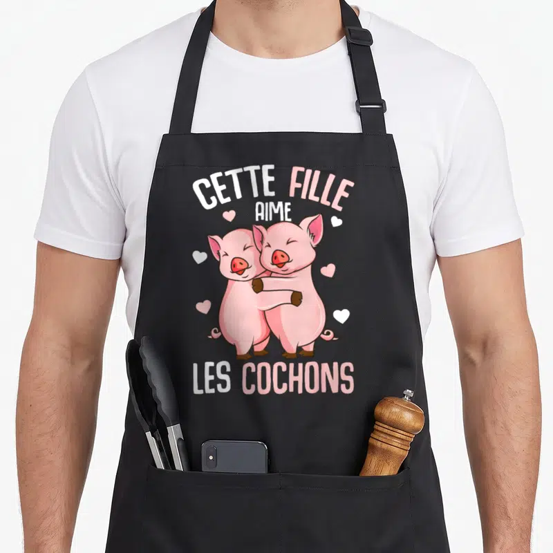 Tablier de cuisine noir avec deux cochons roses s'embrassant et le texte Cette Fille Aime Les Cochons.