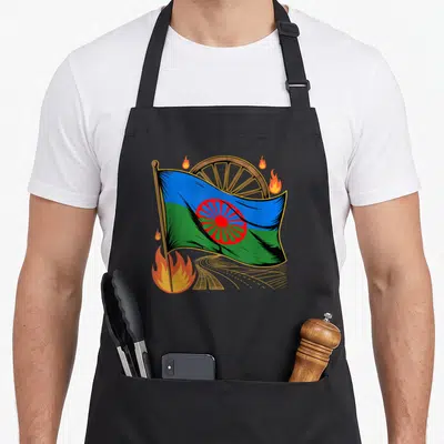Tablier de cuisine noir avec drapeau bleu vert rom, roue en bois et flammes orange stylisées.