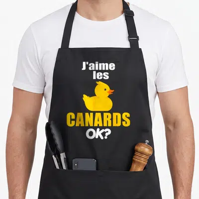 Tablier de cuisine noir avec illustration d'un canard jaune et le texte J'aime les canards OK ?, design humoristique.