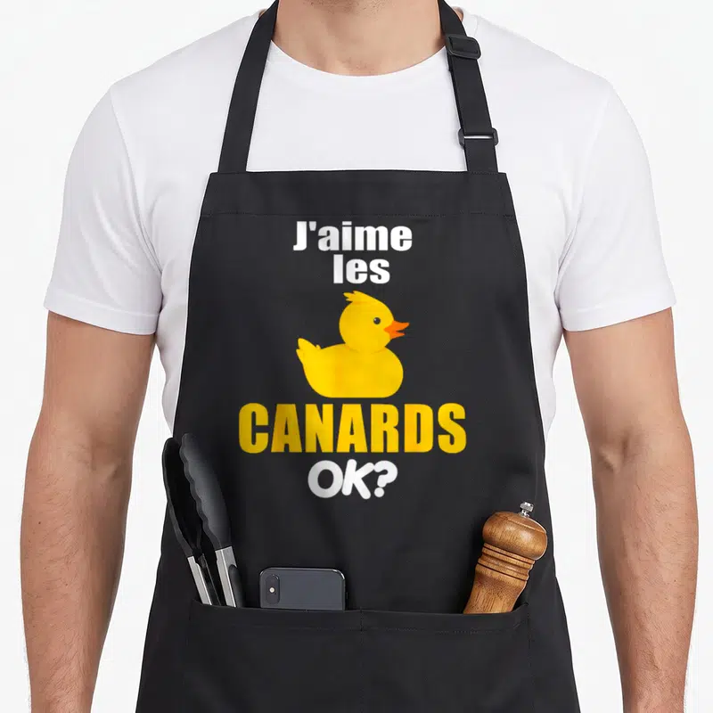 Tablier de cuisine noir avec illustration d'un canard jaune et le texte J'aime les canards OK ?, design humoristique.