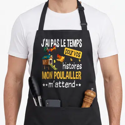 Tablier de cuisine noir avec illustration de poulailler, coq et poussins sous une phrase humoristique en blanc et orange.