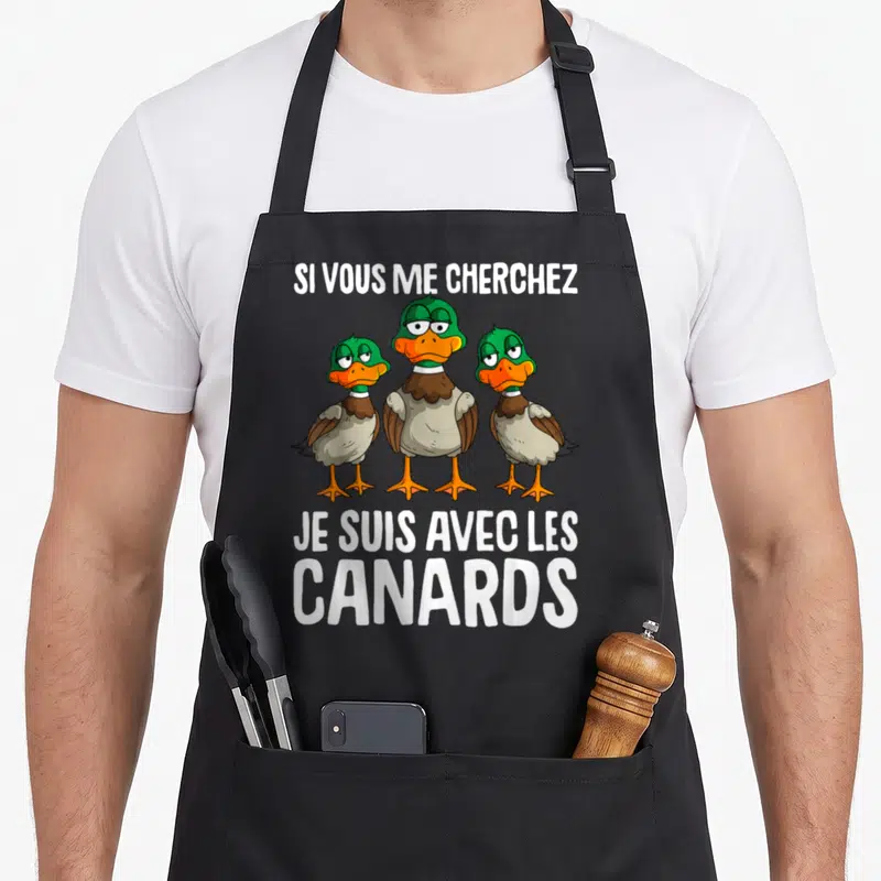 Tablier de cuisine noir avec trois canards dessinés et le texte Si vous me cherchez je suis avec les canards en blanc.