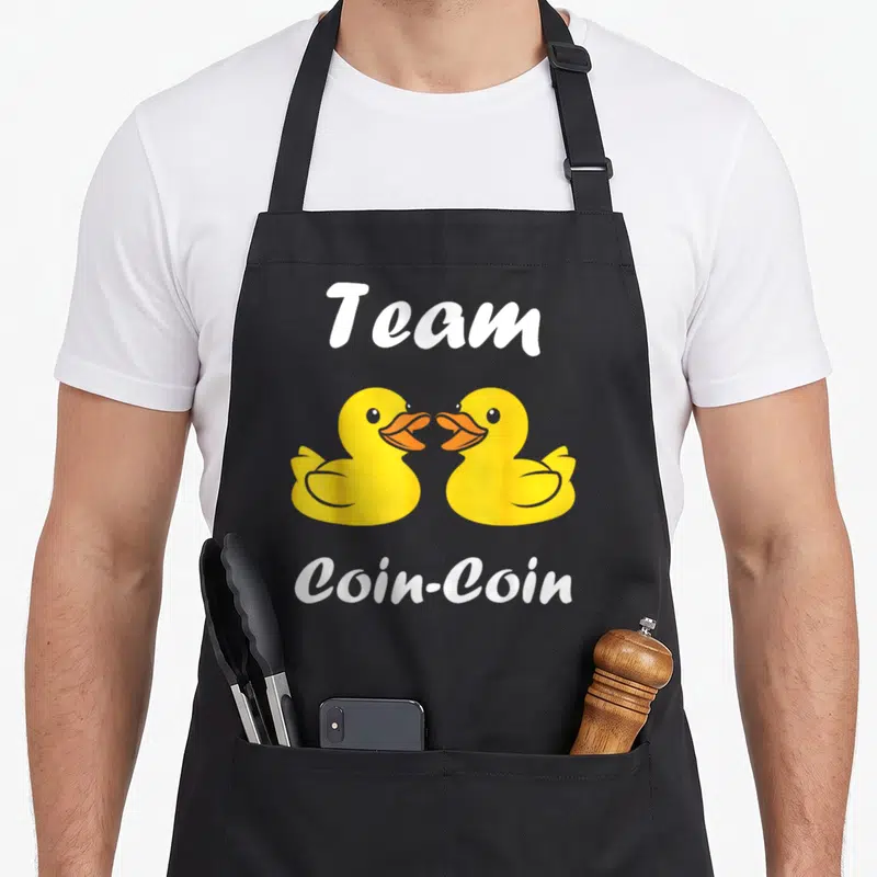Tablier de cuisine noir avec deux canards jaunes et l'inscription Team Coin-Coin en blanc.